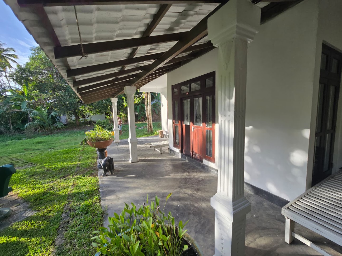 A shaded veranda opening onto a green garden