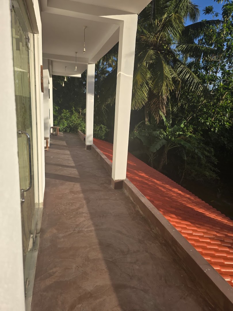 A covered upper veranda with white columns and a view into tropical greenery