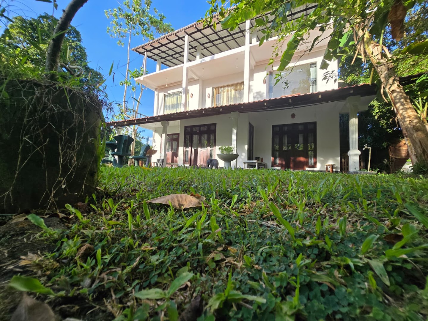 The villa rising behind a green tropical garden under a clear blue sky